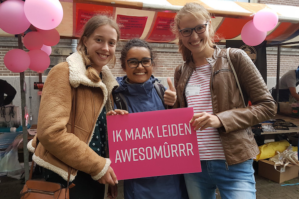 Tres mujeres del capítulo de Amsterdam con un cartel leyendo "Ik Maak Leiden Awesomûrrr"